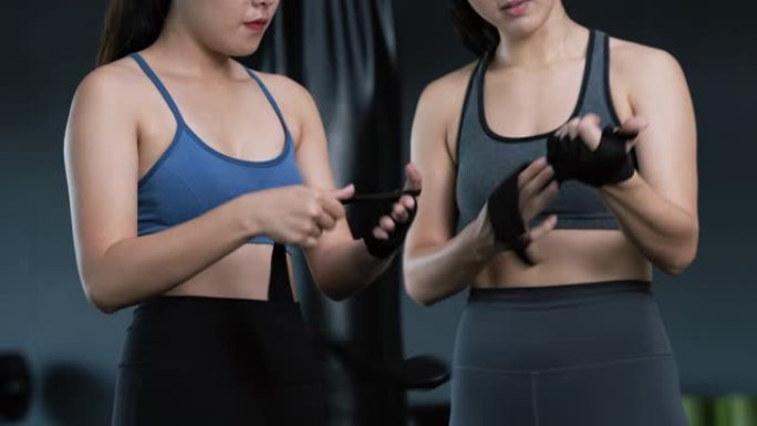 运动年轻的亚洲女性训练拳击手与教练教练一起准备手腕上的绑带，拳击练习运动进行搏击或与健身健身房的伴侣