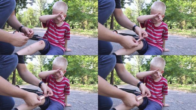 一个四岁男孩从踏板车上摔下来，摔断了膝盖。爸爸通过消毒伤口和涂抹石膏来提供急救。