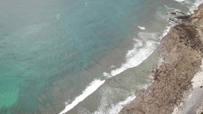 在印度尼西亚弗洛雷斯的科卡海滩，一架田园诗般的无人机拍摄了平静的海水，冲向岸边。海水有晶莹剔透的绿松
