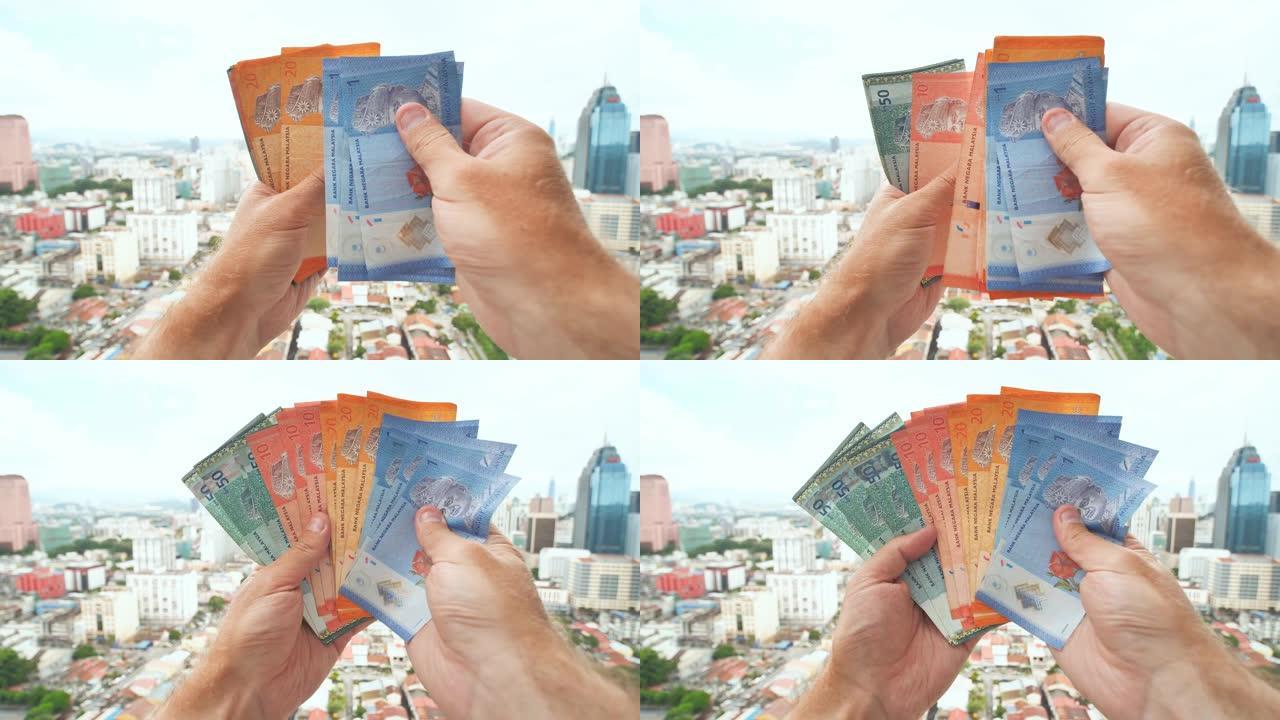 一名年轻人在吉隆坡市中心的背景下用手讲述马来西亚的钱