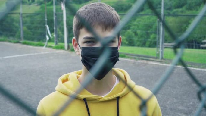 戴着医用防护面具的年轻人在金属网围栏后面