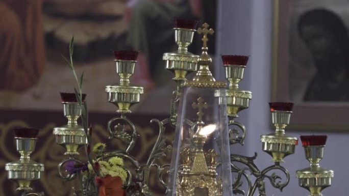 教堂里一个旧烛台的特写。库存镜头。东正教寺庙内部的细节，美丽的烛台，十字架和模糊的图标背景上的花朵