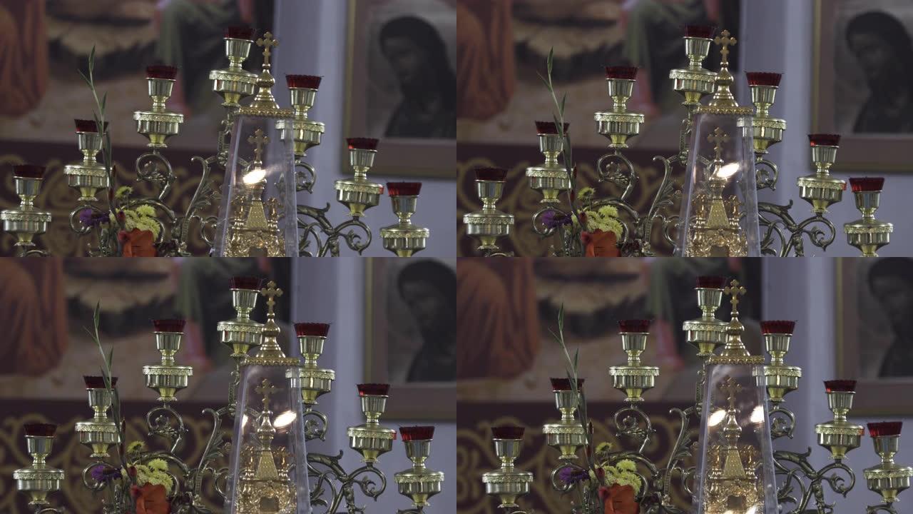 教堂里一个旧烛台的特写。库存镜头。东正教寺庙内部的细节，美丽的烛台，十字架和模糊的图标背景上的花朵