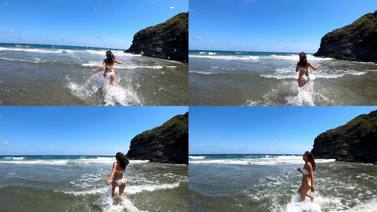 夏天在海滩上穿着比基尼的辣妹在水里奔跑