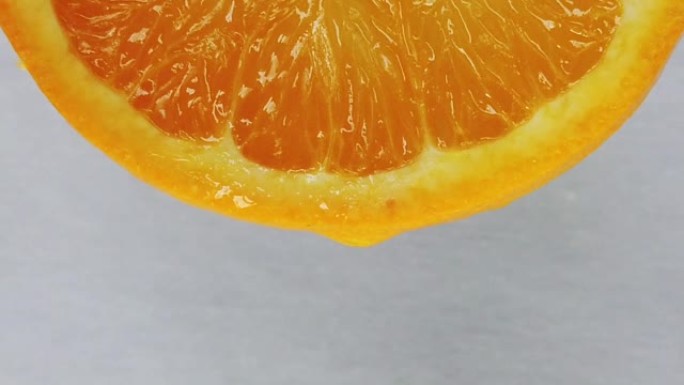慢动作镜头。一滴水从橙色新鲜水果切片上滴下来。带有噪音和burry bokeh背景。