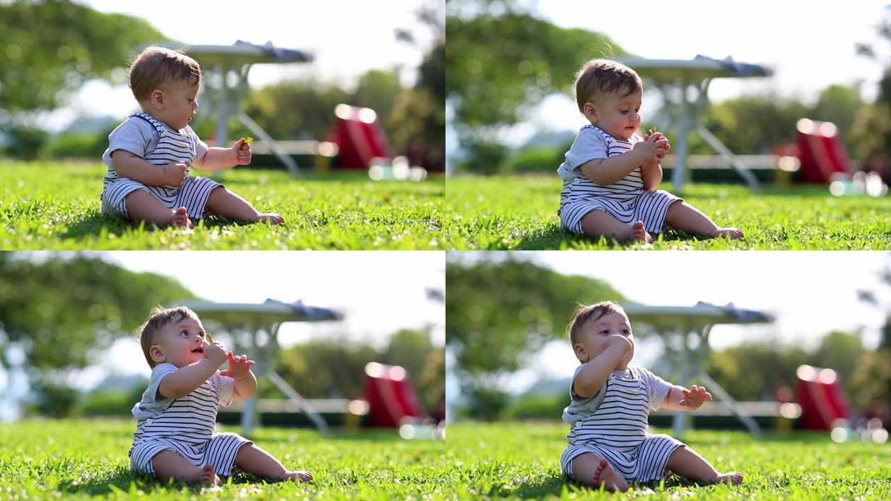 婴儿坐在公园外面的大自然采摘一片叶子，探索世界的孩子