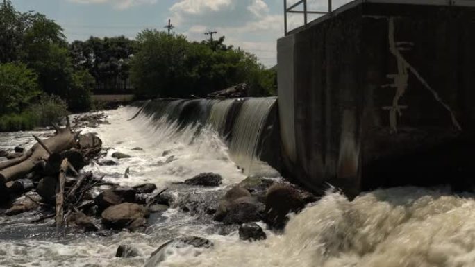 平移水的侧面视图或瀑布流流过一个人的混凝土大坝到下面的河流。