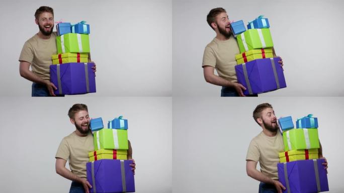 快乐的大胡子家伙庆祝生日，走路，小心翼翼地拿着许多礼品盒，看着相机