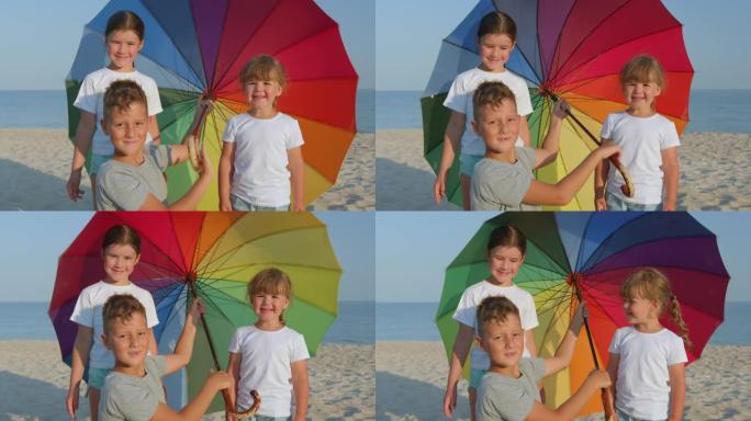 快乐的孩子在海滩上打着伞旋转。彩虹伞。晴天。