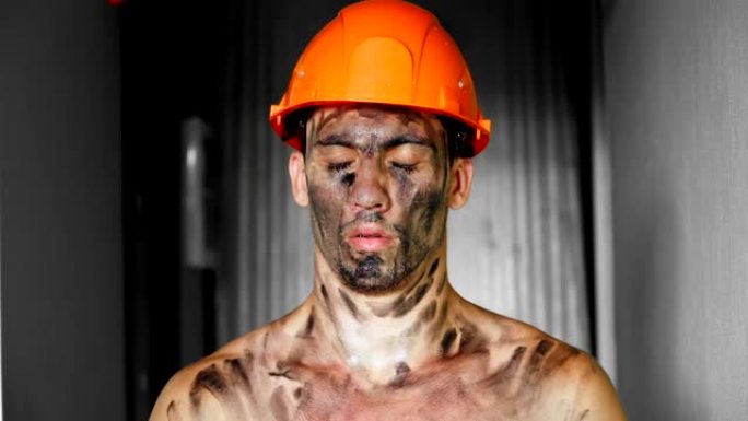 肖像工人下班后累了，浑身是泥。在建筑工地上辛苦工作。戴头盔的筋疲力尽的人。