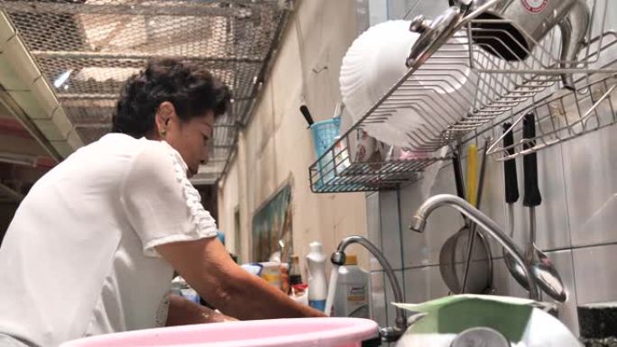 亚洲高级女性在家厨房洗碗，生活方式理念。