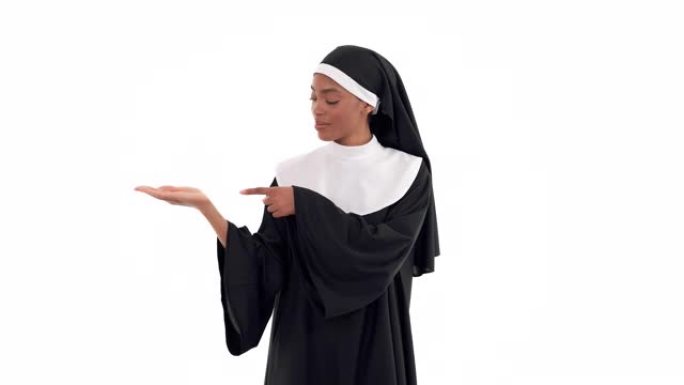 非裔美国修女的肖像举起她的右手，指着她张开的手掌上看不见的东西。孤立在白色背景上
