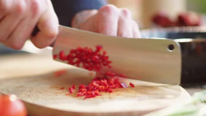 在木制砧板上煮红辣椒的手