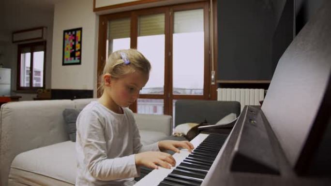小女孩在家弹钢琴。孩子在客厅弹钢琴。孩子在家学习钢琴。音乐课，中景正面视图。