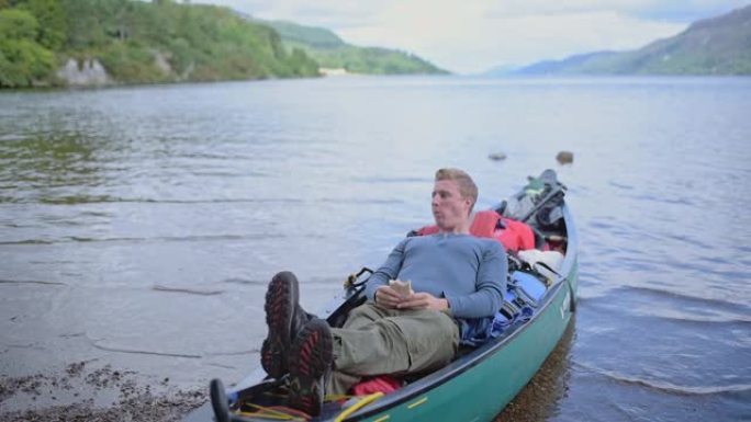 一个年轻人在苏格兰喀里多尼亚运河河上的船上休息时吃饭-特写镜头