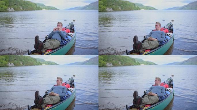 一个年轻人在苏格兰喀里多尼亚运河河上的船上休息时吃饭-特写镜头