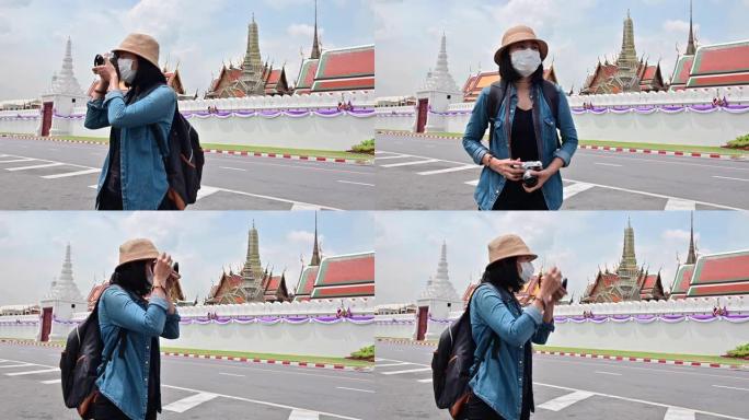 4k戴着医用口罩的旅游妇女在曼谷大皇宫拍照