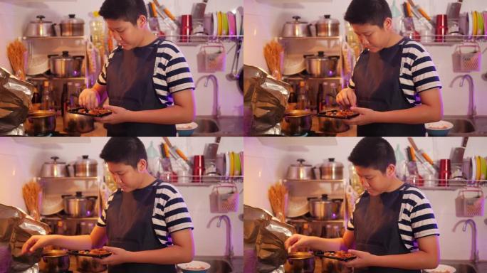 亚洲青春期男孩用发光二极管灯在厨房为家庭准备食物。