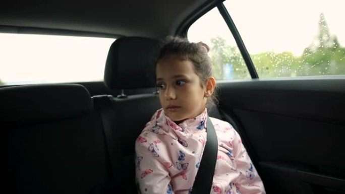 女孩坐在汽车后座上，在上学的路上与朋友聊天