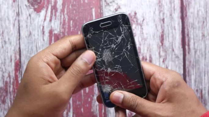 男子手持破碎智能手机的特写。
