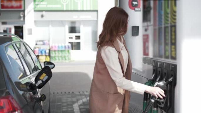 汽油价格，漂亮的女孩在加油站给车加油，女孩在加油站把燃油喷嘴插入汽车油箱