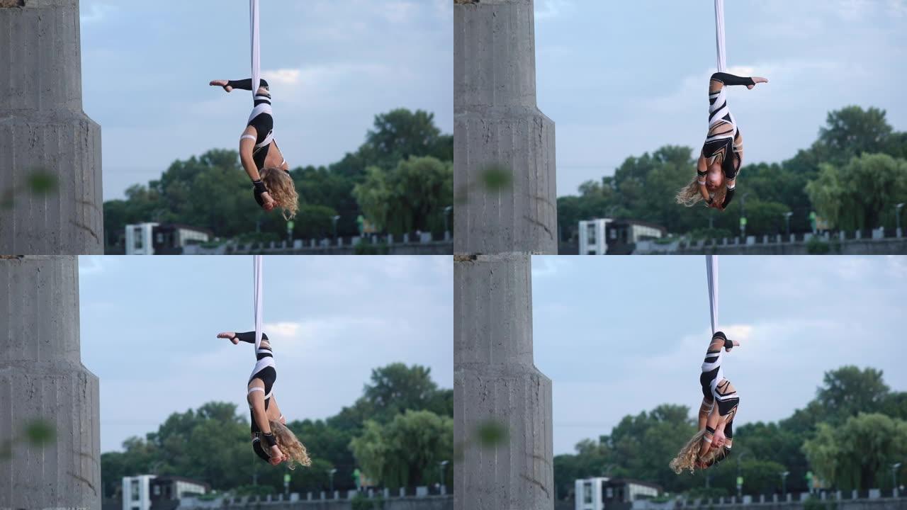 童女空中飞人表演杂技元素，并在悬挂的空中丝绸中旋转。