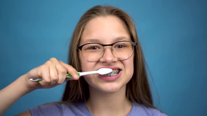 带牙套的女孩用牙刷特写刷牙。一个牙齿上有彩色牙套的女孩保持牙齿清洁。