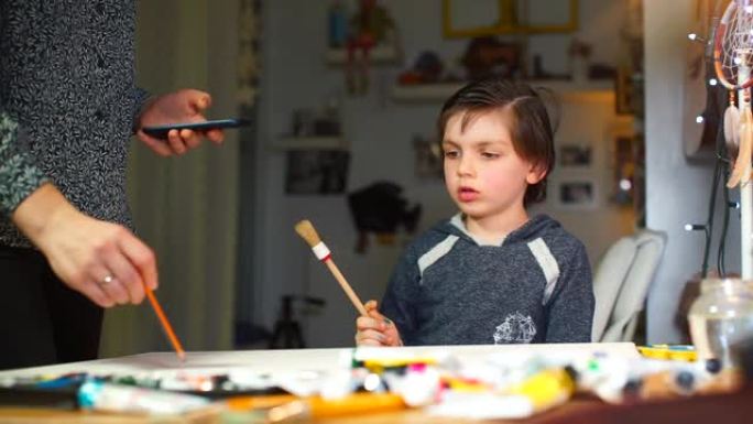 手握画笔的男孩在艺术创作过程中与妈妈交谈