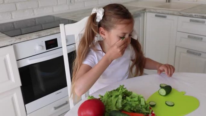 孩子在厨房吃健康食品。孩子在眼前拿着黄瓜杯子
