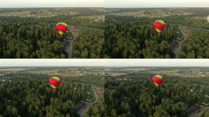 夏天日落时，在蓝天的背景下，气球在绿色的田野和森林上飞行。无人机射击