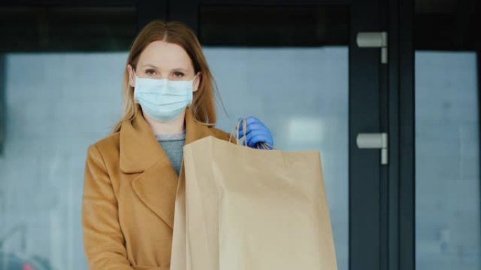 在进入杂货店的背景下，戴着手套和口罩的女人带着一袋杂货
