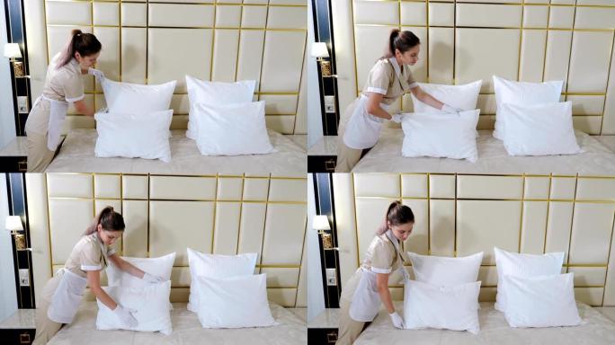 酒店清洁概念。穿着制服的年轻漂亮女仆的肖像在明亮的房间里铺床，触摸枕头，打成形状。准备酒店房间。4 