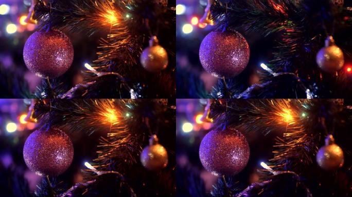 圣诞球与闪光挂在圣诞树上的绿色针闪烁的花环的黑暗背景。粉色圣诞装饰特写