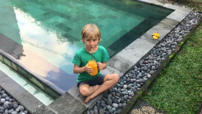 小男孩用不锈钢吸管从玻璃杯中喝水果冰沙。减少塑料的使用。在电话上拍摄