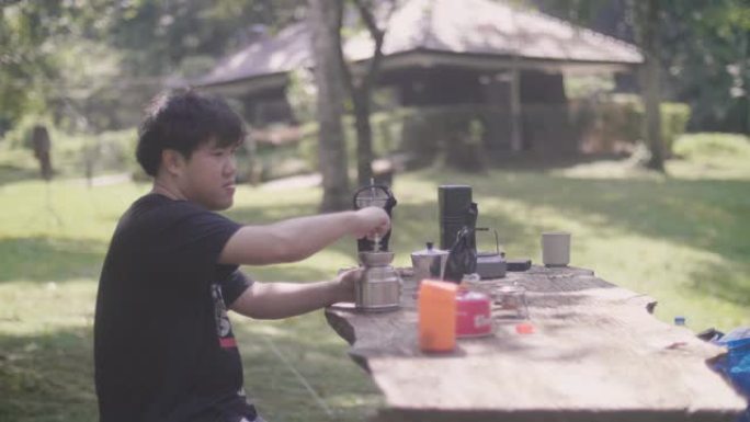 年轻的亚洲人在大自然的晴天煮咖啡。