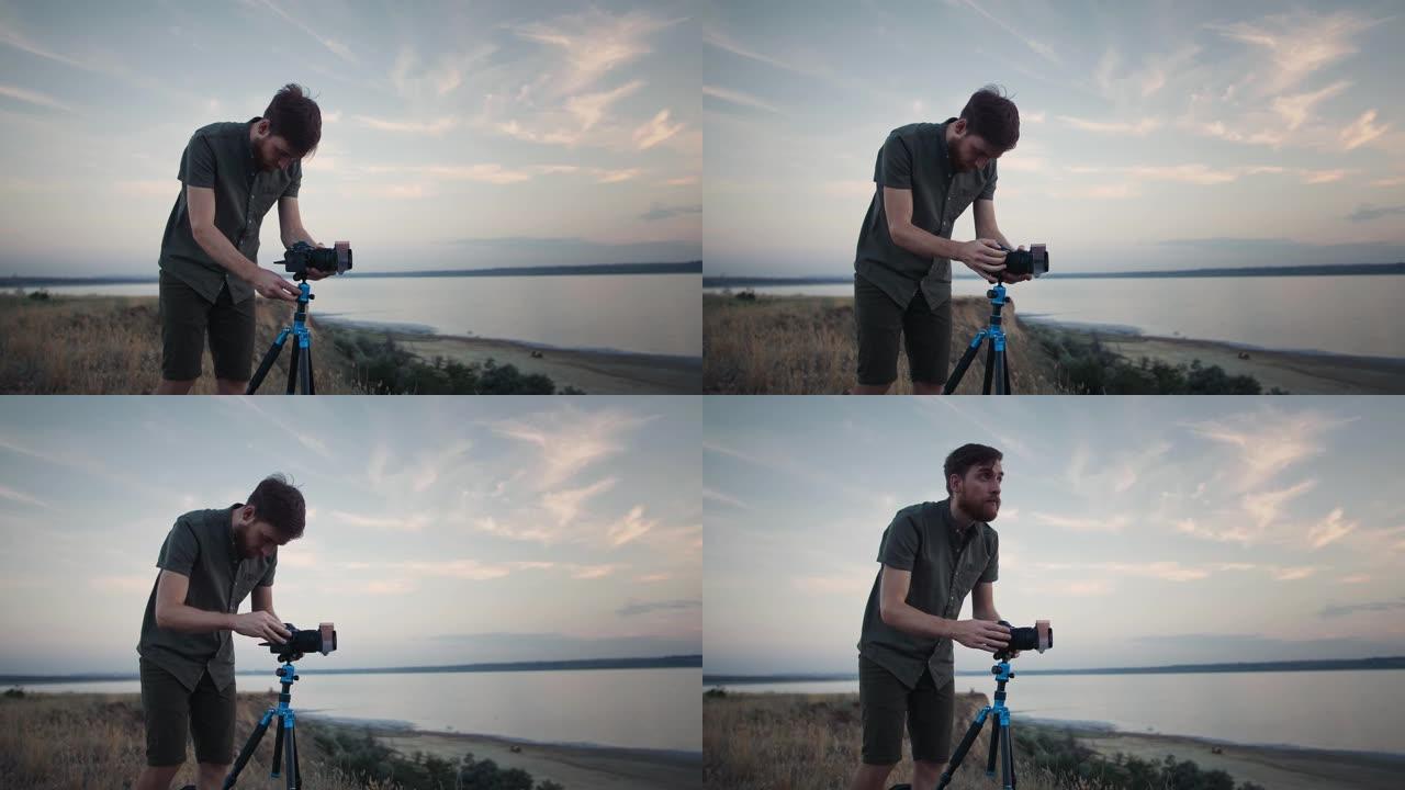 盖伊摄影师站在高高的山坡上，调整相机上的滤光器固定在三脚架上，然后进行拍摄。湖上风景如画