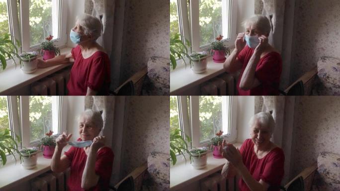 新型冠状病毒肺炎、健康、安全和流行病概念 -- 戴着防护医用口罩的老年孤独妇女坐在家里的窗户附近，防