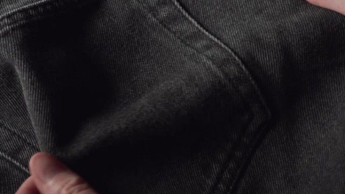 一个妇女在纺织品商店触摸黑色棉布牛仔裤面料