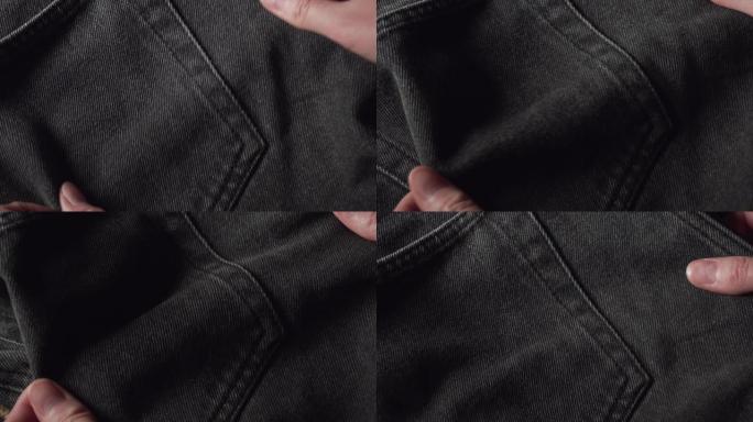 一个妇女在纺织品商店触摸黑色棉布牛仔裤面料