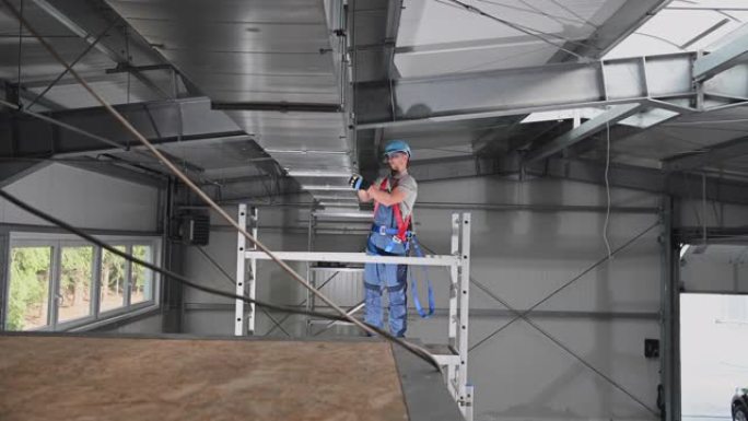 高加索男性建筑工人将已安装的空调竖井的零件紧固在新建筑的天花板上。