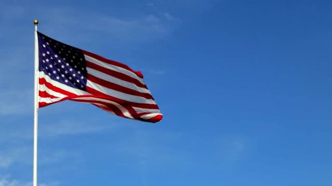 美丽的美国国旗在风中飘扬，充满活力的红、白、蓝颜色映衬着蓝色的天空，有着复制的空间。