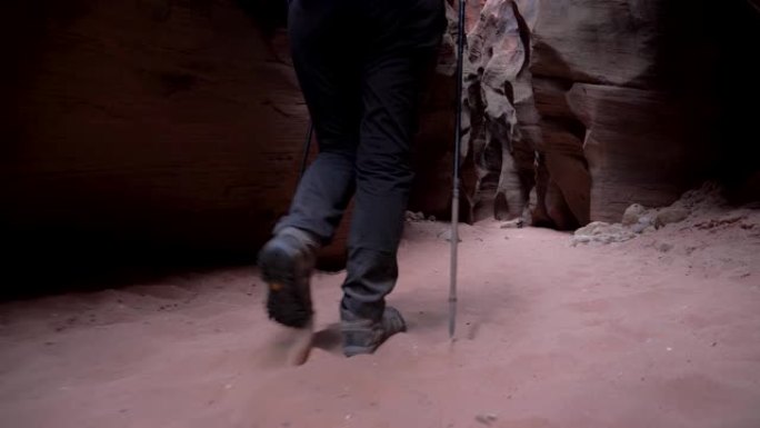 腿部徒步旅行者在狭缝峡谷干燥的河床徒步旅行，拥有光滑的砂岩墙