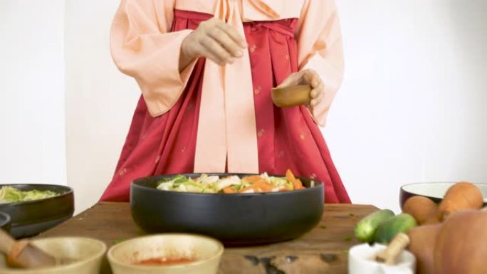 穿着韩服韩国传统服装的亚洲女性正在烹饪泡菜