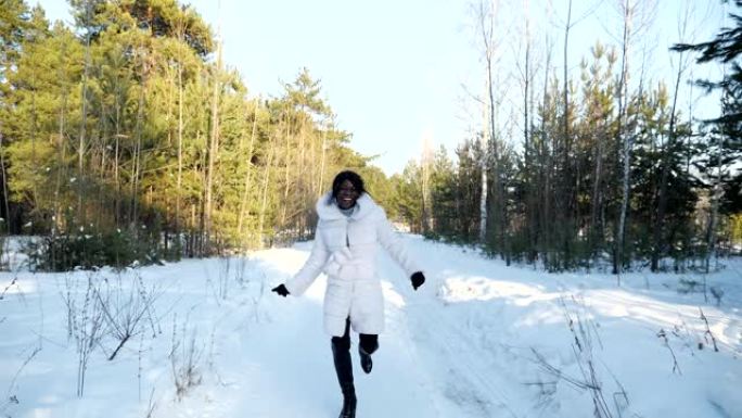 非裔美国女孩在冬季森林中沿着雪道奔跑