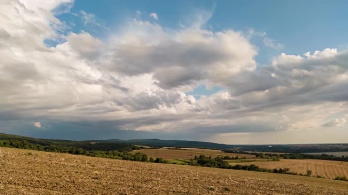雨云在乡村丘陵和麦田上空移动的时间流逝