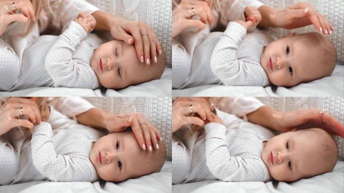 特写关爱母亲的手抚摸着躺在床上的可爱的婴儿的头。用4K红色相机拍摄