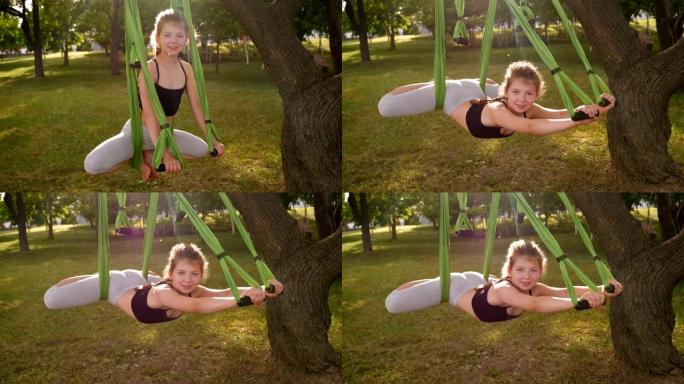 一个小女孩正在树园做飞行瑜伽。一个孩子在吊床上做瑜伽。