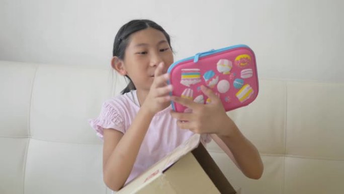 快乐的亚洲女孩在家里网上购物后开箱。