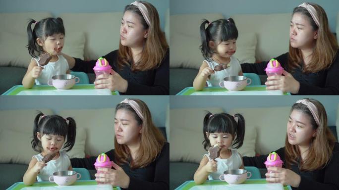 细心的母亲在家吃冰淇淋时照顾女儿