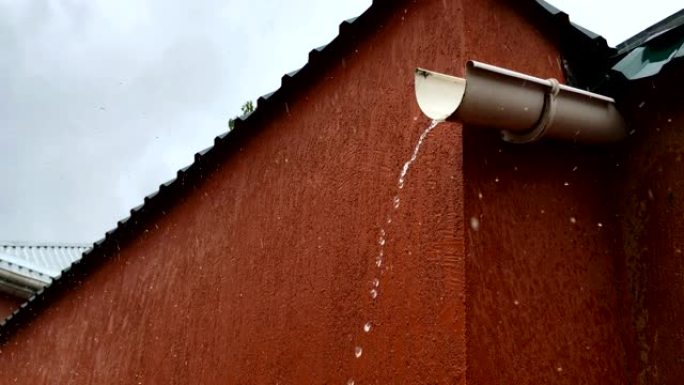 雨时水流从塑料排水管滴下。